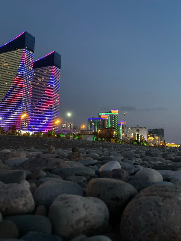 Batumi's pebble shore and glowing skyline at dusk