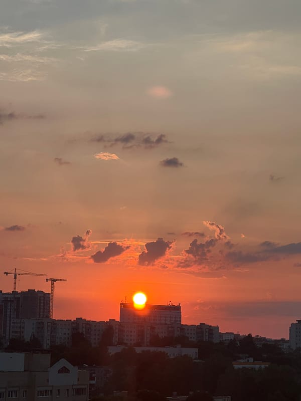 Minsk sunset, sun dipping behind city buildings