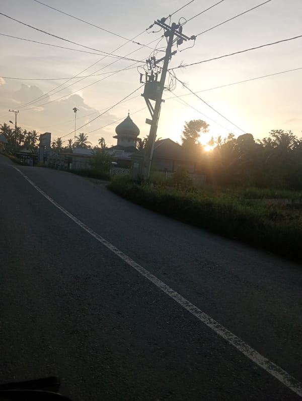 Sunset illuminates road to domed building in Lhokseumawe