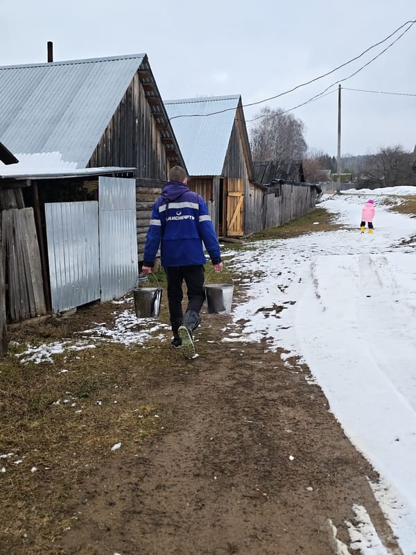 Grandmother feeds young children during quiet morning in Уральское