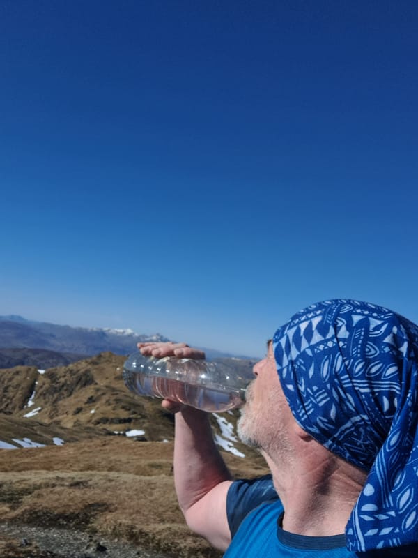Man drinks water bottle in Scottish Highlands morning scene