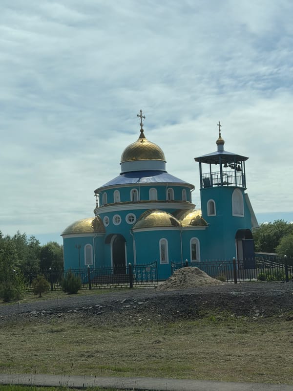 Boy pulls cart near turquoise church in Smidovich, Russia