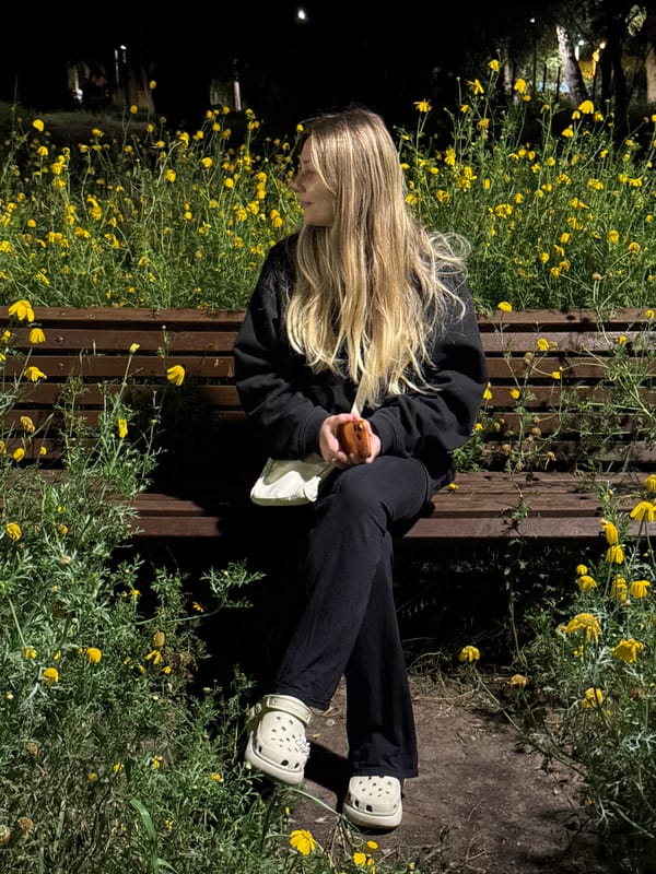 Woman sits among yellow wildflowers on Tel Aviv park bench