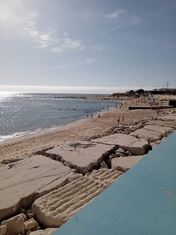 Beachgoers gather at coastal area with damaged concrete barrier