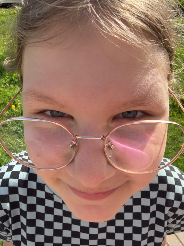 Woman in strawberry hoodie photographed applying makeup outdoors
