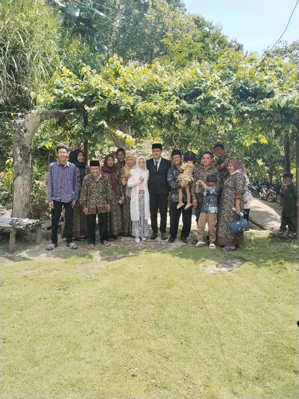 Fourteen people pose for group photo under tree