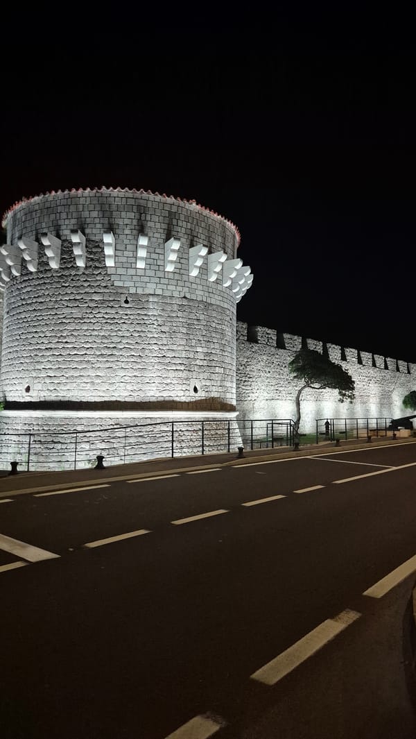 Ancient stone fortress at night, town surroundings nearby