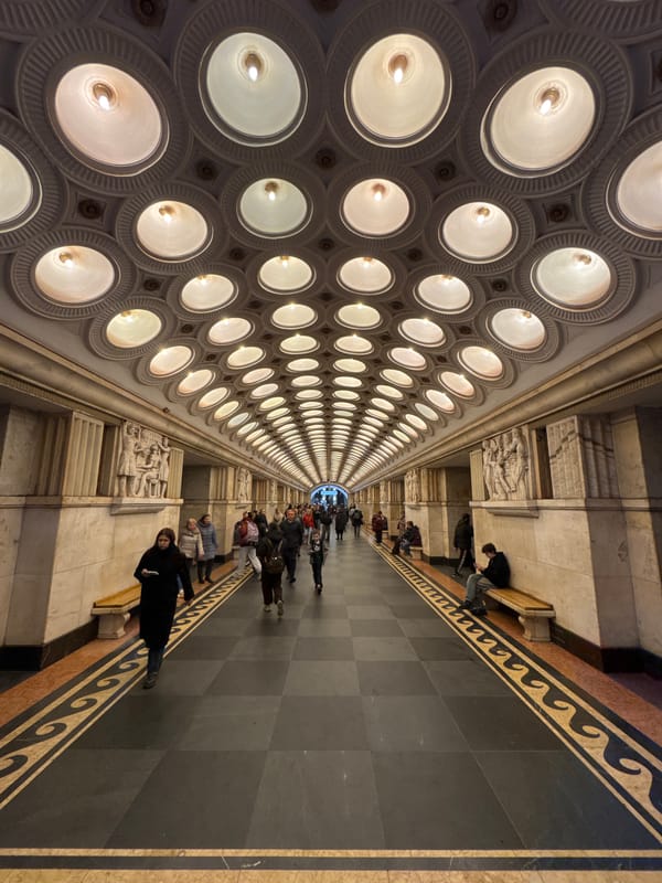 People walk through corridor with grid-pattern ceiling lighting