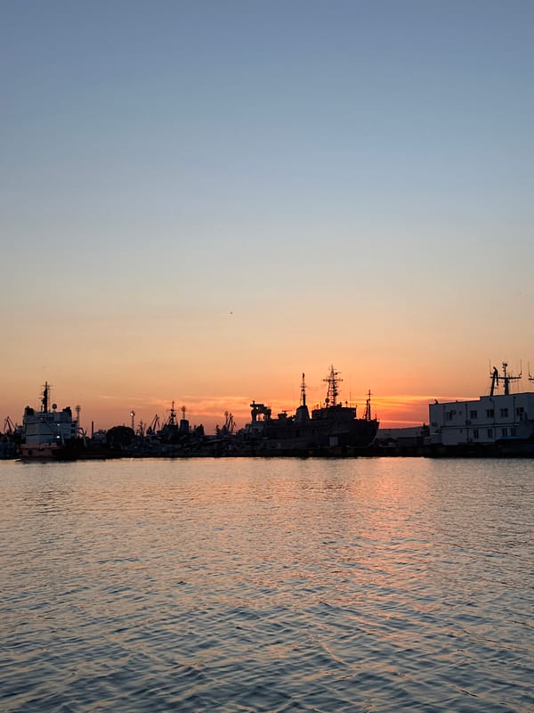 Sunset boat trip across calm water near an industrial port