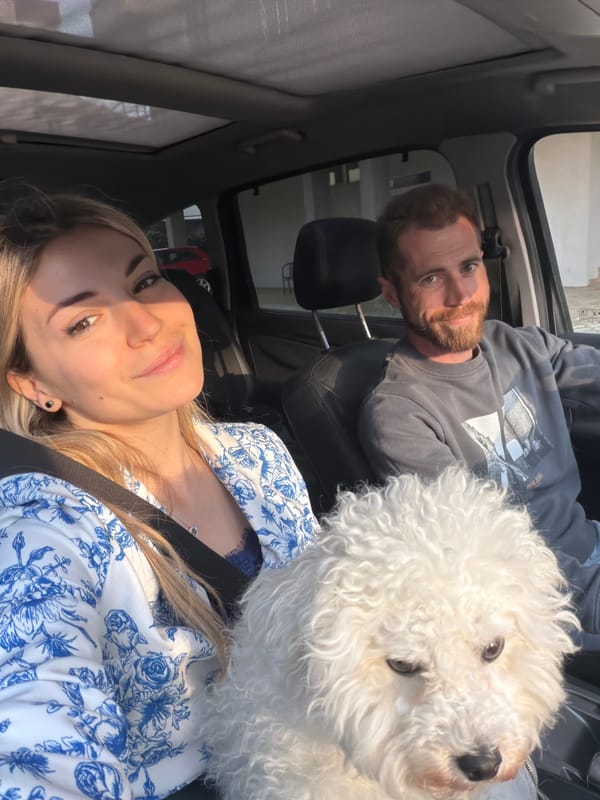 Couple travels with fluffy white dog through sunny Budva