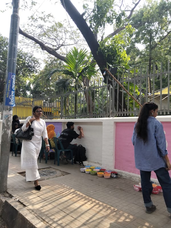 Pedestrians cross paths on Dhaka sidewalk during morning hours