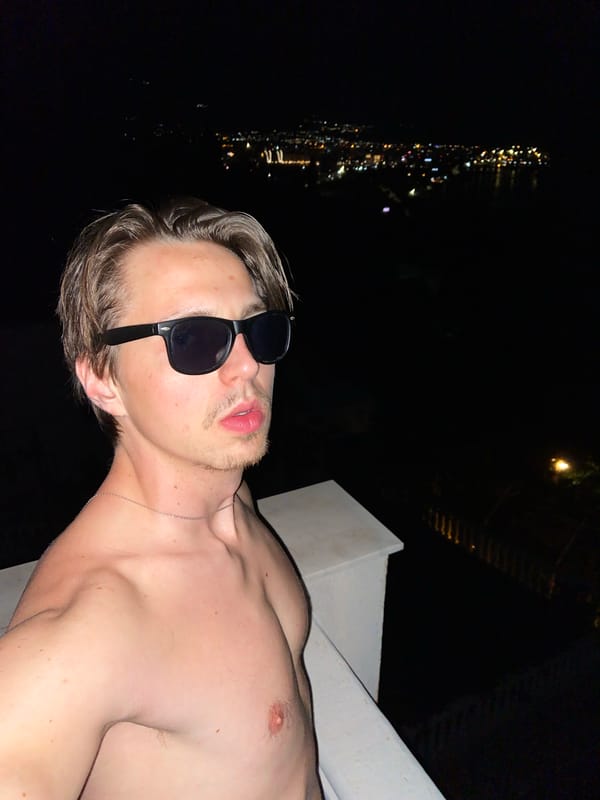Man poses for nighttime photos on ledge in Šušanj