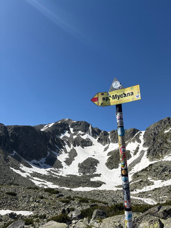 High-altitude Bulgarian mountain terrain with snow patches and signpost