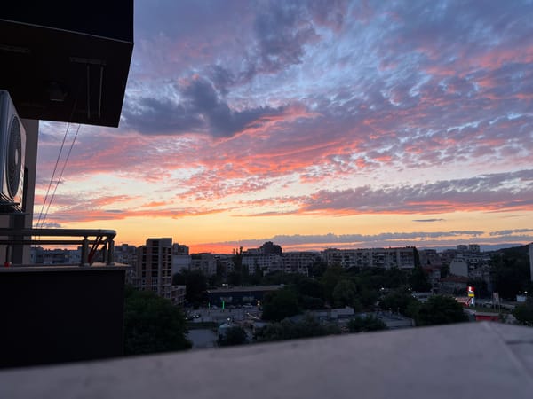City skyline at sunset, pink and purple clouds overhead.