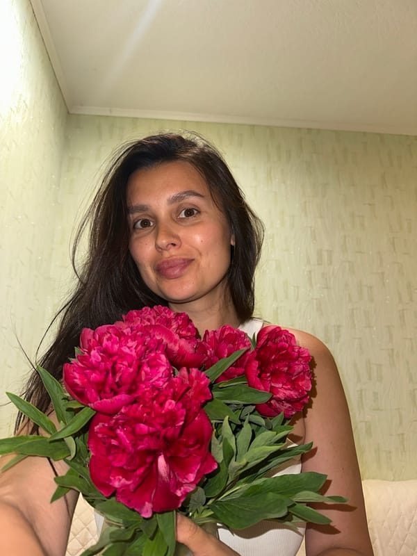 Woman spends afternoon with cat and peonies in Chaikovsky