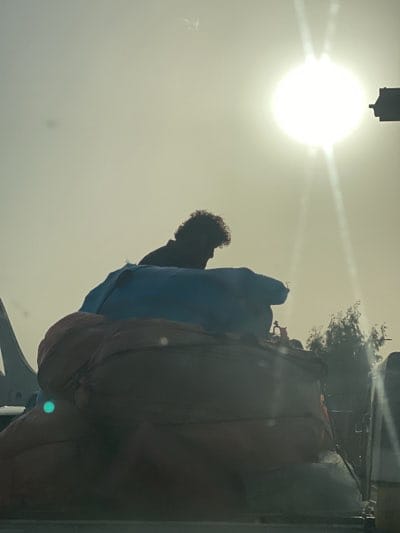 Man sits atop colorful bundle pile in Kandahar