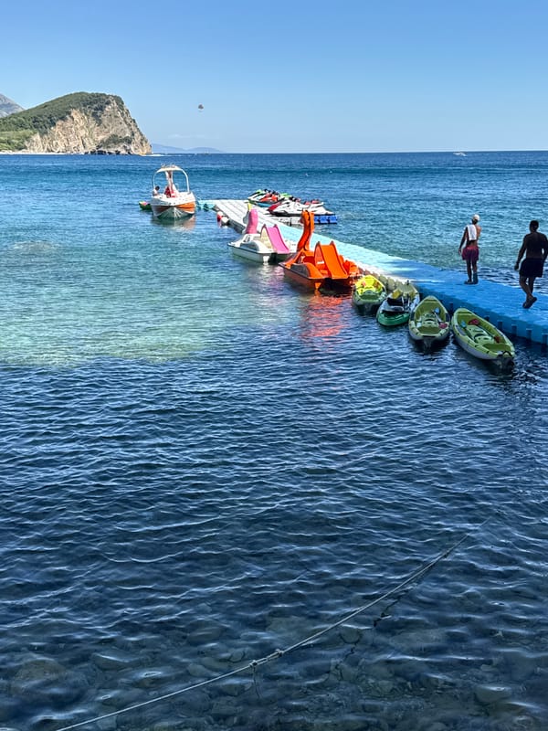 Summer afternoon on the Budva waterfront — piers, sea, and old town
