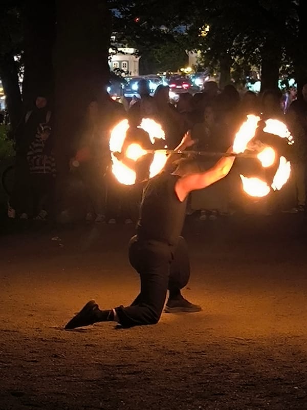 Fire performer juggles flames for outdoor crowd at night