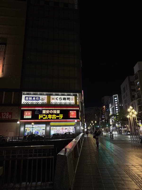 Wet nighttime street scene captured near Don Quijote in Fukuoka