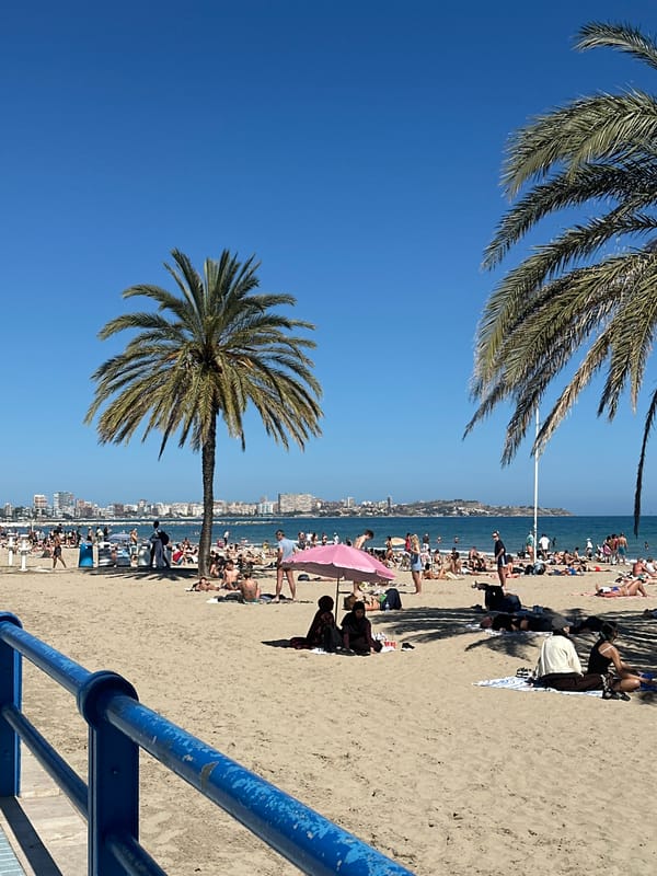 Busy beach day in Alicante features sunbathing and parasailing