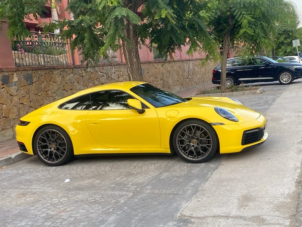 Yellow Porsche 911 parked on cobblestones in Estepona