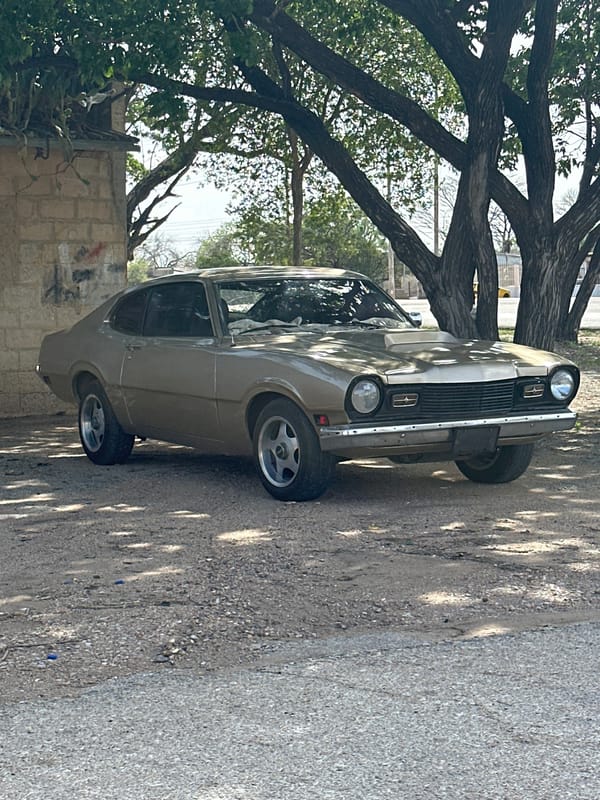 Vintage gold Ford Maverick parked under trees in Venezuela