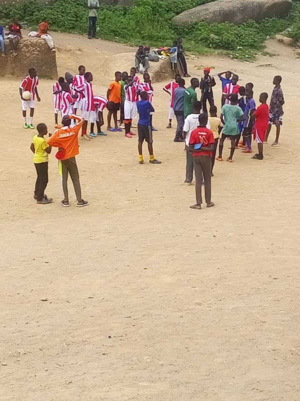 Street football in Jos, framed by Nigeria's granite boulder landscape.