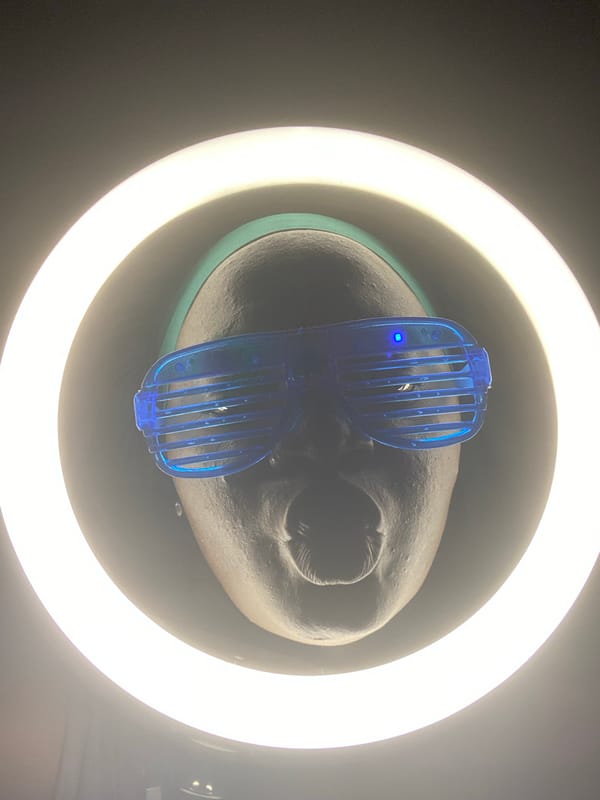 Person poses with blue sunglasses under ring light in Nigeria