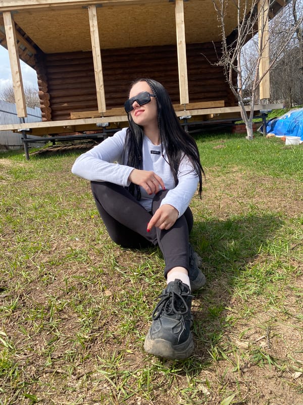 Woman sits outdoors with shopping bag in Chaikovsky, Russia