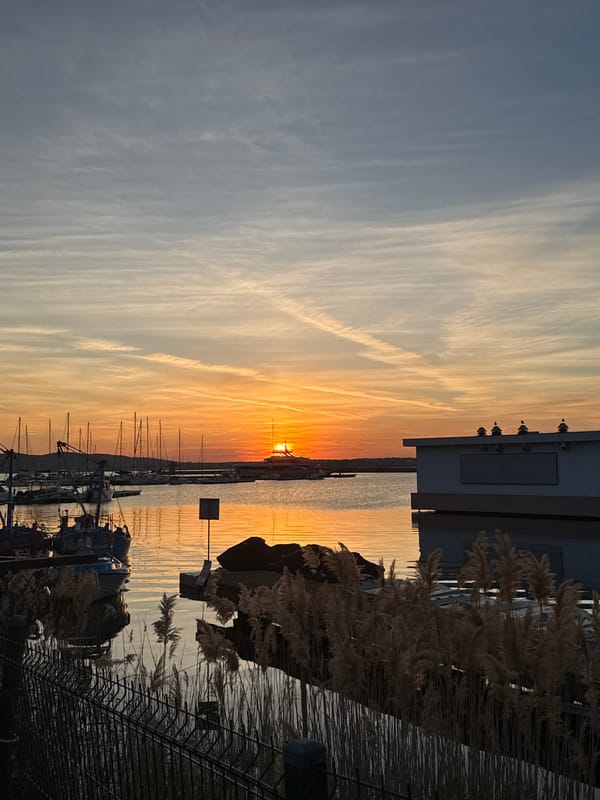 Sunset documented at Sozopol harbor with boats and contrails
