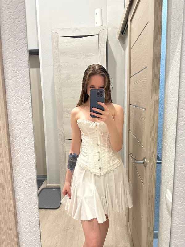 Woman takes mirror selfie in white outfit