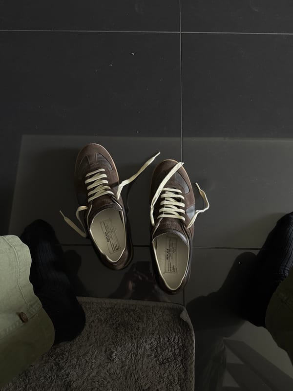 Brown suede sneakers spotted on dark tiles in London