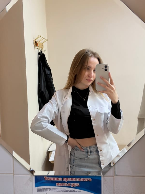 Woman in lab coat takes mirror selfie in Chaikovsky