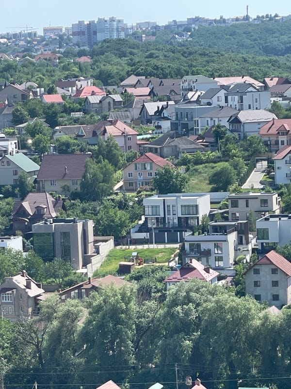 Aerial views of a hillside neighborhood with forest edge and local streets