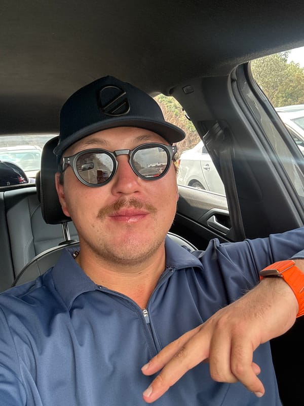 Man in navy cap makes peace sign in car