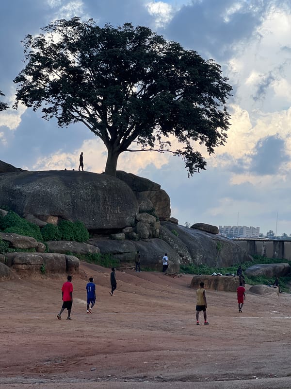 Football on a dusty pitch among Jos Plateau's rocky landscape