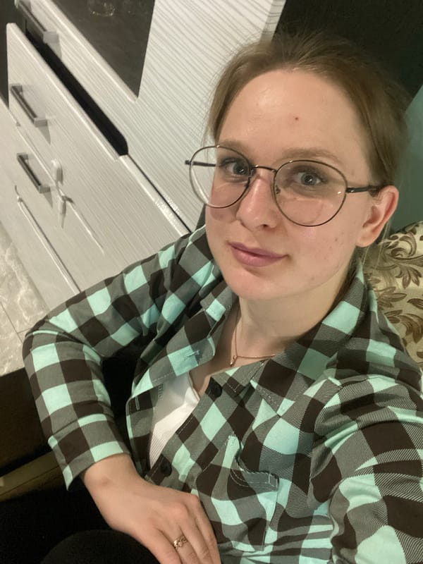 Woman in flannel shirt observed indoors holding white object
