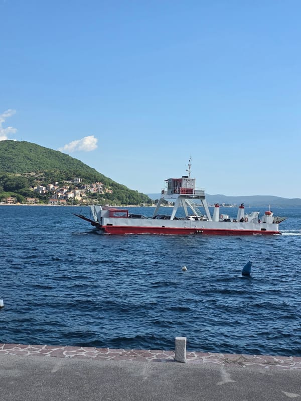 Ferries cross calm waters near Đurići, Montenegro coastline