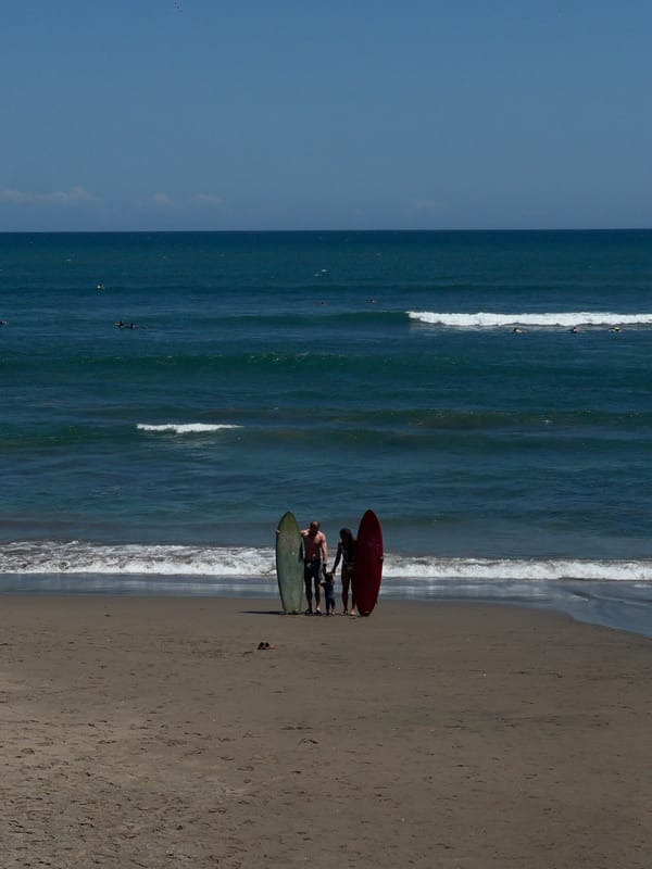 Family with surfboards enjoys morning beach time in North Kuta