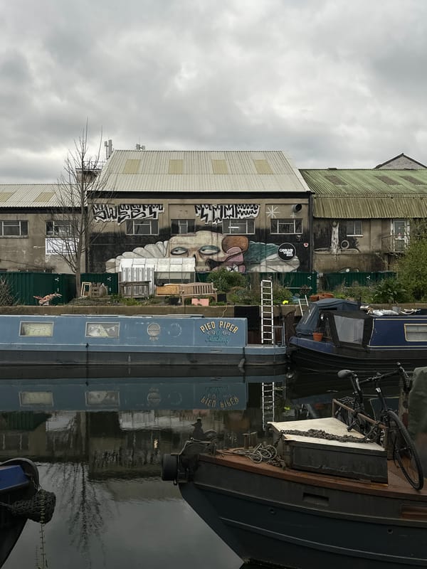 London canal scene features industrial building with face graffiti
