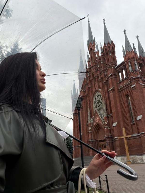 Clear umbrella in hand outside Moscow's Gothic red brick architecture