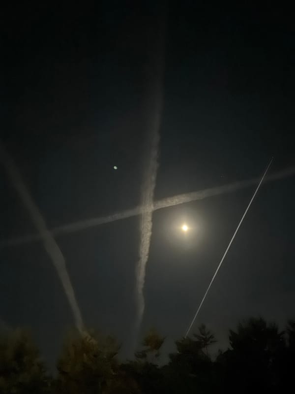 Intersecting aircraft contrails form X-patterns over Mishutkino night sky
