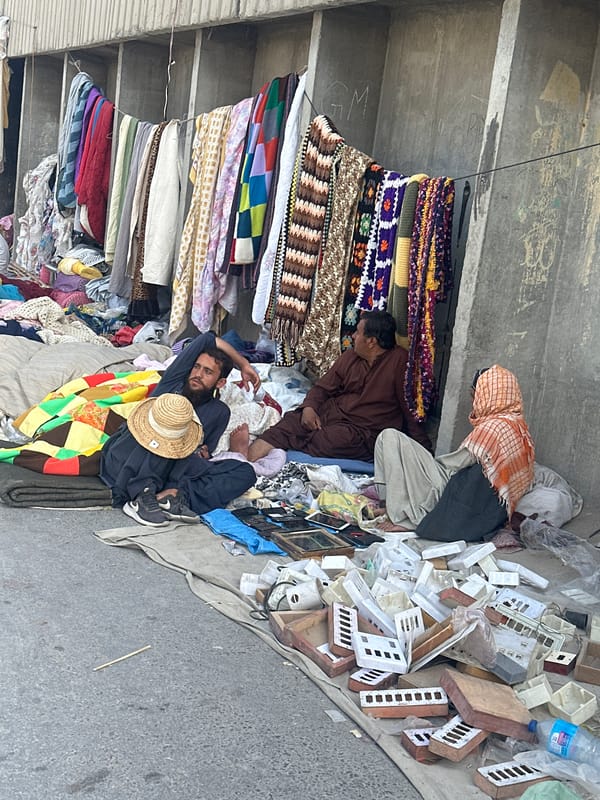 Street vendor rests as shopper passes Quetta market stalls