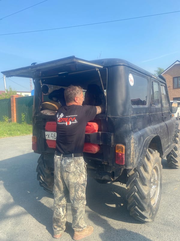 Man stands behind open SUV on residential street in Artyom