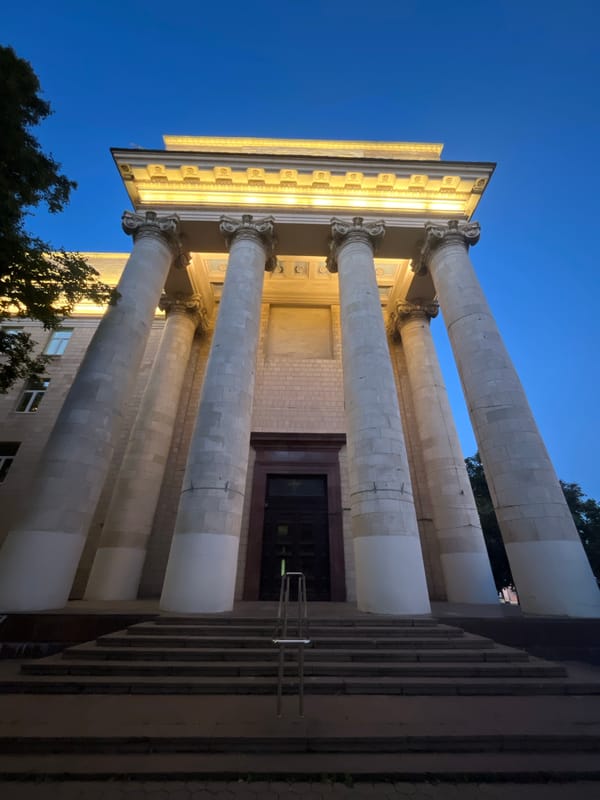 Classical architecture, vintage truck, and memorial bust at a heritage site