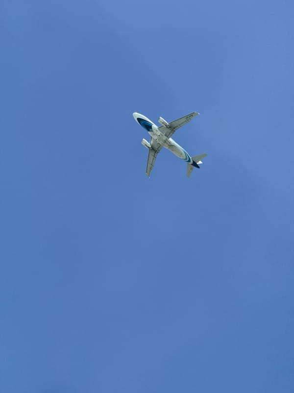 Weathered fishing harbor and passing plane, Baan Plai Laem