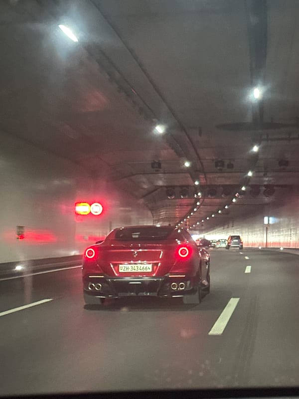 Red sports car travels through Zurich tunnel during afternoon traffic