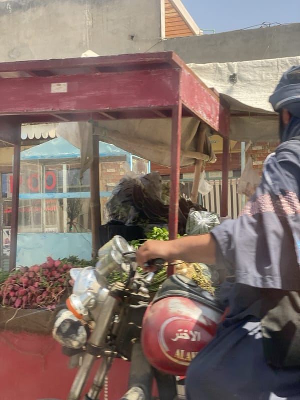 Motorcyclist passes vegetable stand in Arghandab, Afghanistan