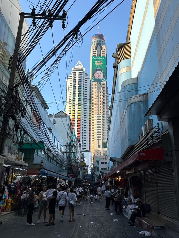 Bangkok street scene shows typical electrical wires, sidewalk vendors