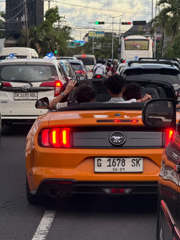 Traffic jam blocks vehicles including orange Mustang in Kuta